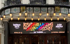 Colourful lettering shows the 'Joseph and the Amazing Technicolour Dreamcoat' sign above a lit theatre marquee