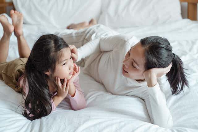 mother and daughter talking on bed