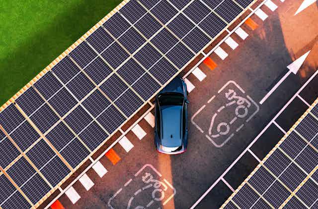 An EV pulls into a parking spot under solar panels.