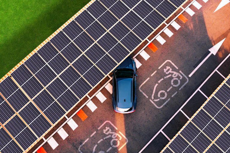 An EV pulls into a parking spot under solar panels.
