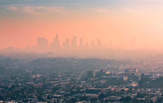 A layer of thick smog hovers over Los Angeles, obscuring tall buildings in the background.