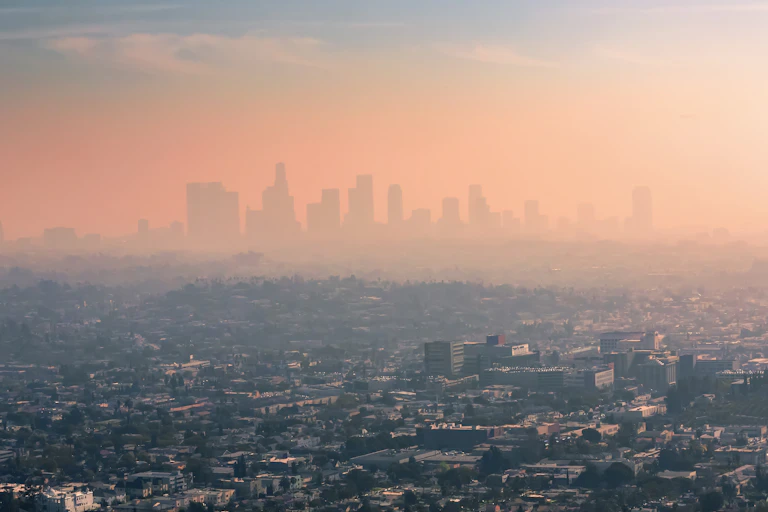 A layer of thick smog hovers over Los Angeles, obscuring tall buildings in the background.