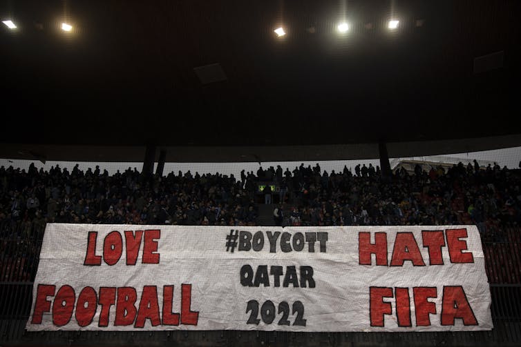 Aficionados del FC Zúrich sostienen un cartel que dice 'ama el fútbol, odia a la FIFA, boicotea a Catar 2022'