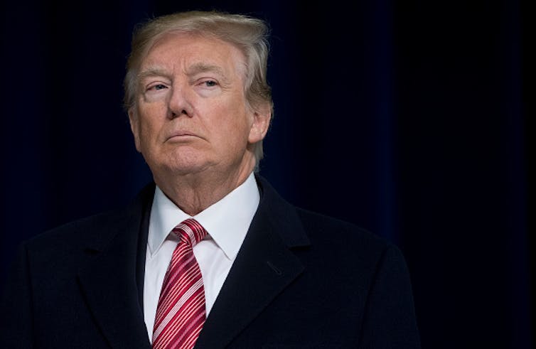 A man wearing a suit, shirt and tie appears in a pensive mood.