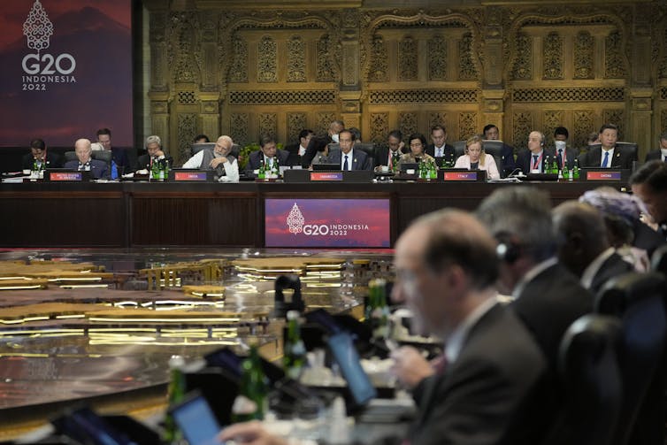 Group of world leaders seated behind desks with G20 signs