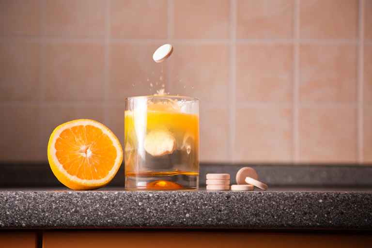 Media naranja y un vaso junto a unas pastillas.