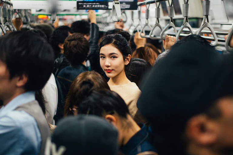 A woman looks at the camera from inside a packed metro carriage