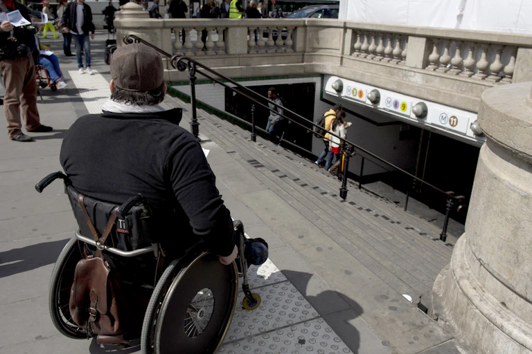 Un homme handicapé en fauteuil roulant distribue des tracts en haut des escaliers d'une station de métro alors qu'il participe à une manifestation à l'appel de l'Association des paralysés de France (APF) pour réclamer plus d'accessibilité dans leur vie quotidienne, le 13 mai 2014 à Paris.