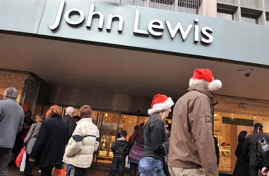 Customers walk past a John Lewis shopfront wearing red Santa hats