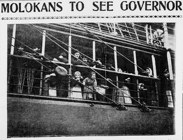 People of varying ages look over the rails of a ship.