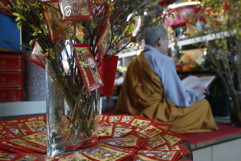 A man reading from a book at a Buddhist temple.