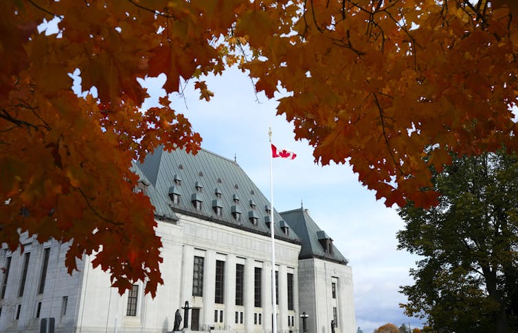Orange autumn leaves and the Canadian flag fram the Supreme Court building