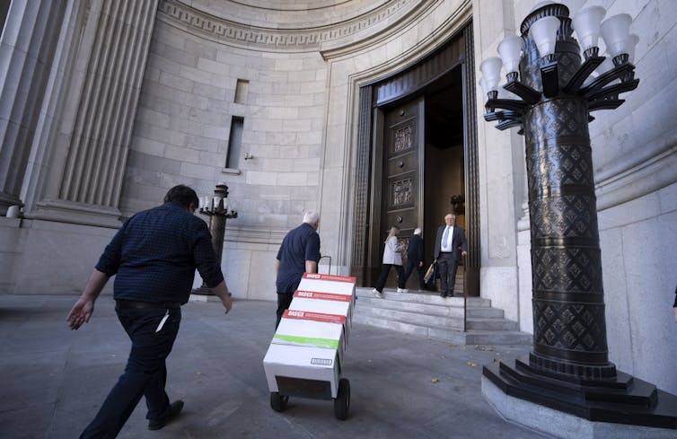 A man wheels boxes of documents into a courthouse.