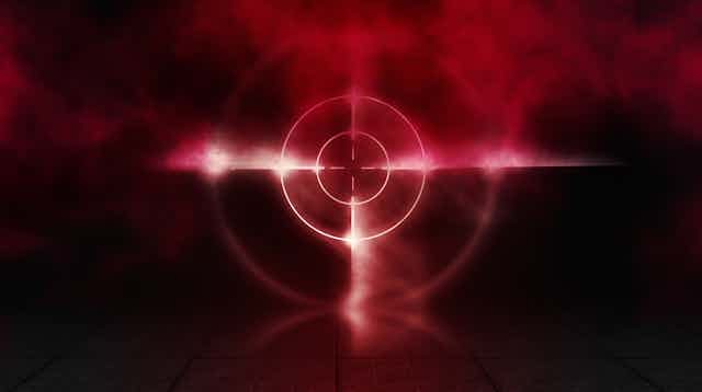 Conceptual image of a red target against a dark background with smoke around it. 