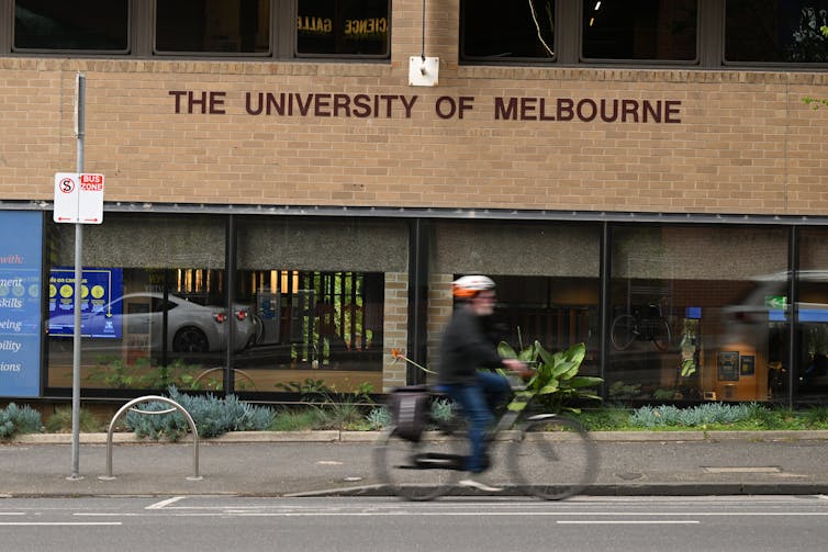 Bike rider goes past Melbourne University building.