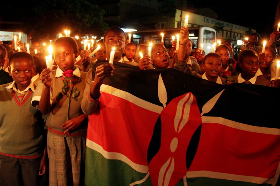 Children in school uniform holding candles and the Kenyan flag.