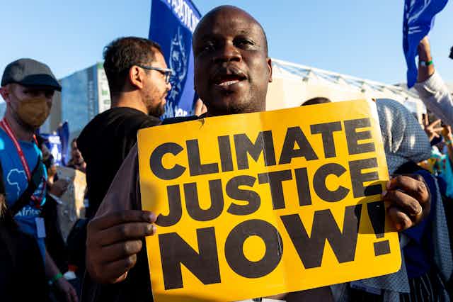 Man holds 'climate justice now' sign