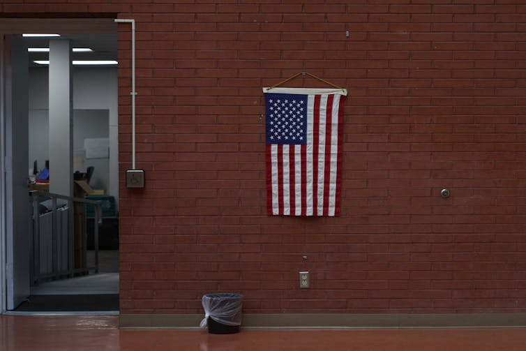 US flag on wall near litter bin.
