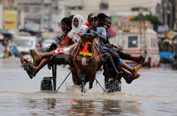 Horse pulls cart filled with people through flooded street