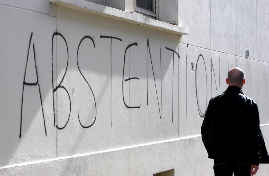 Un homme marche le long d'un mur sur lequel le mot "abstention" a été tagué, le mardi 16 mars 2010 à Caen.