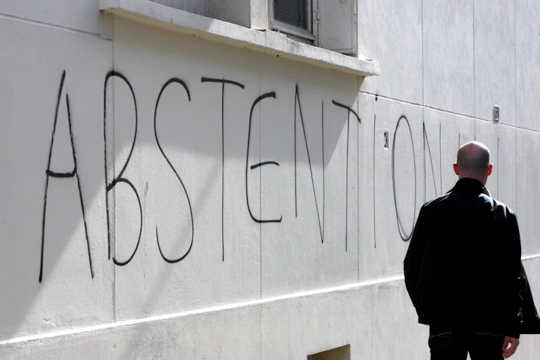 Un homme marche le long d'un mur sur lequel le mot "abstention" a été tagué, le mardi 16 mars 2010 à Caen.