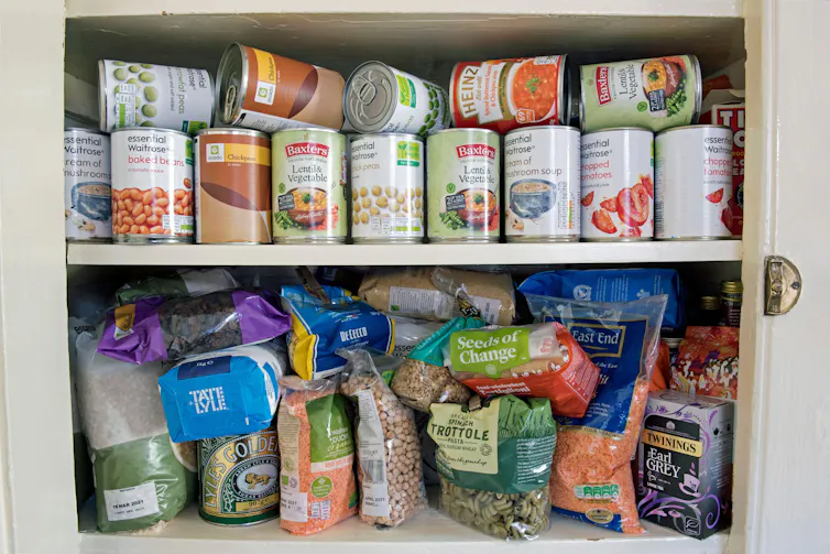 Tinned and packets of dried food, stockpiled tins of produce stored in cupboard, stockpiling due to the coronavirus corvid 19 pandemic lockdown London UK.