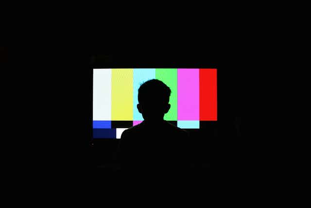 An illustration of a silhouette of a boy watching the test pattern on a television.