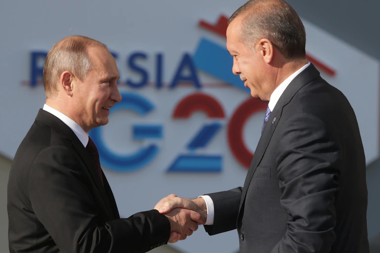 Two men in suits shake hands.