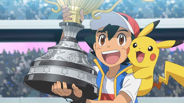 Ash Ketchum, with Pikachu on his shoulder, holds his World Championship trophy aloft
