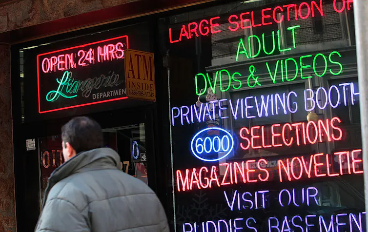 Man walks by window advertising adult videos.
