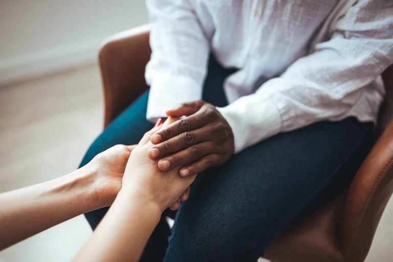 Two pairs of hands holding one another.