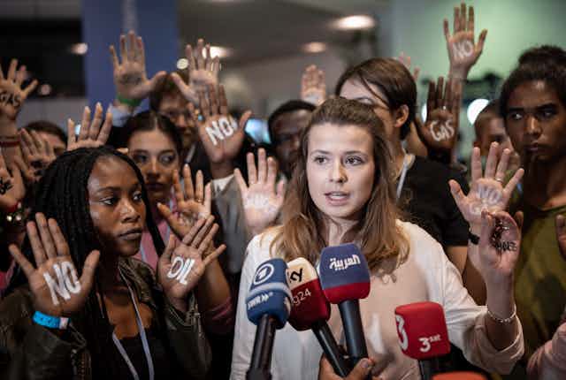 Young activists hold up their hands "No oil" and "no gas" written on them during a press conference.
