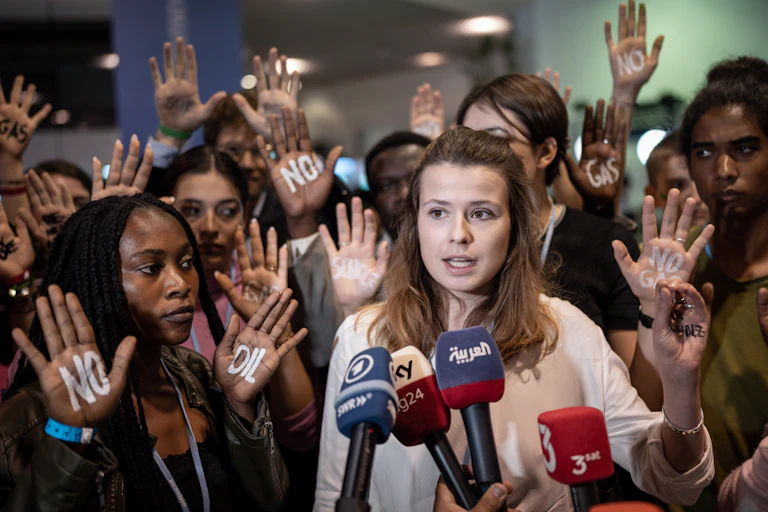 Young activists hold up their hands "No oil" and "no gas" written on them during a press conference.