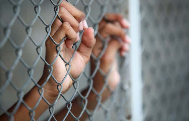 Child hands on prison fence