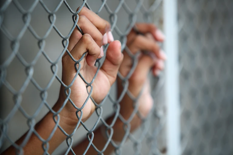 Child hands on prison fence