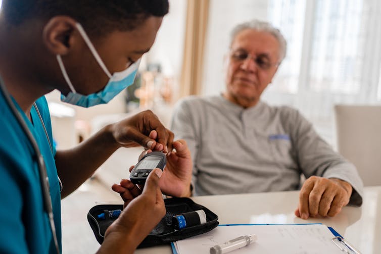 A man having his blood sugar measured by a doctor or nurse