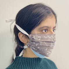 A person wearing a cloth face mask over a surgical mask