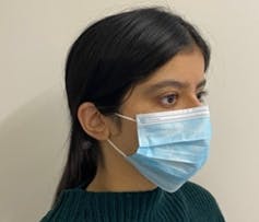 A person wearing a blue surgical face mask