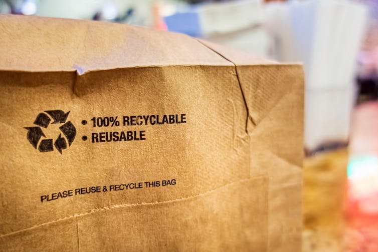 A brown paper bag with the text 100% recyclable and reusable printed on the bottom.