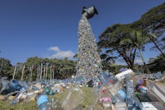 Uma escultura gigante de lixo plástico saindo de uma torneira.