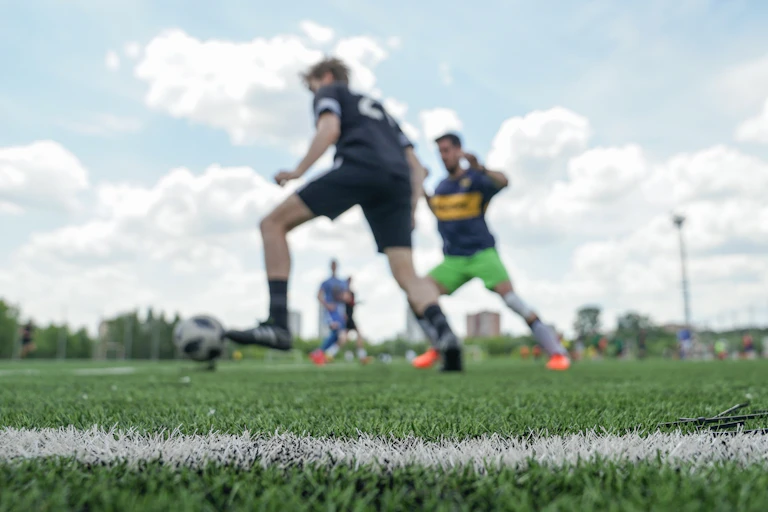 Amateur male football players, out of focus, playing on a pitch