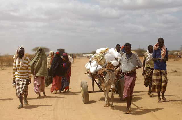 Un grupo de personas avanza por un camino en un paisaje seco.