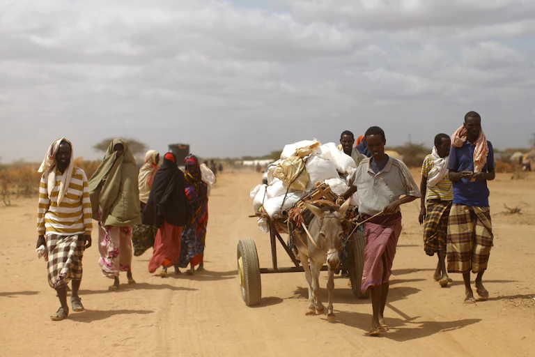 Un grupo de personas avanza por un camino en un paisaje seco.