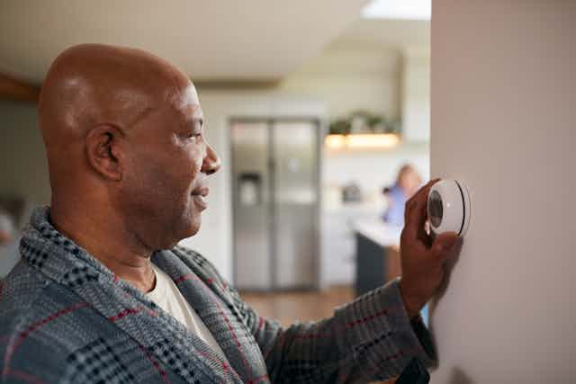 Man looks at digital thermostat