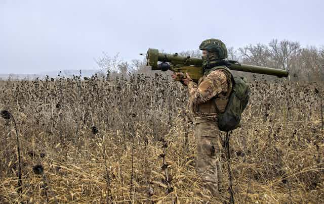 Soldier in a field carrying a rocket launcher