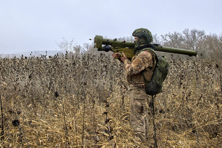 Soldier in a field carrying a rocket launcher