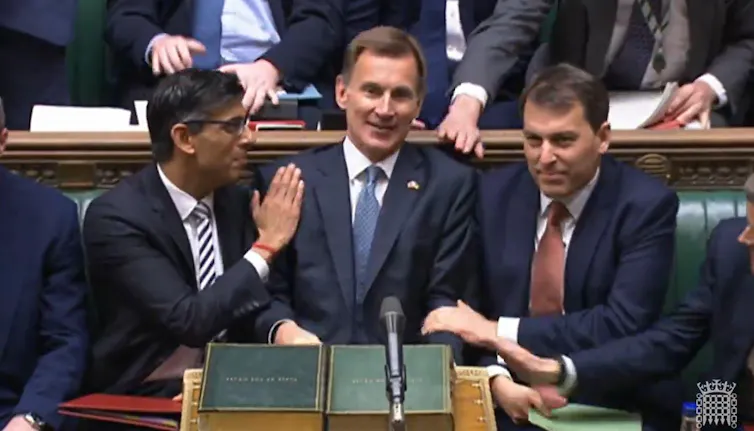 Rishi Sunak patting Jeremy Hunt on the shoulder on the front bench of the House of Commons.