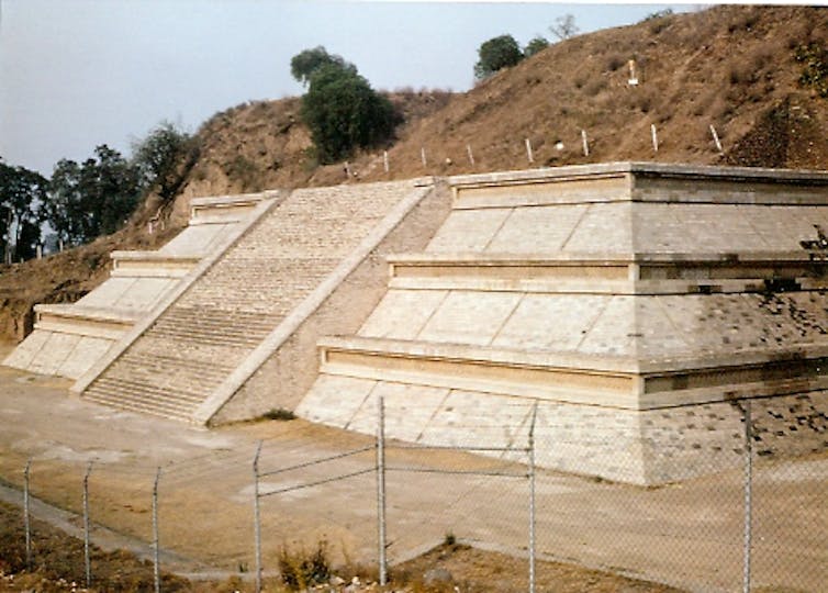 Step pyramid structure with earth mound on top.