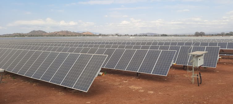 Rows of solar panels mounted at an angle in a desert.