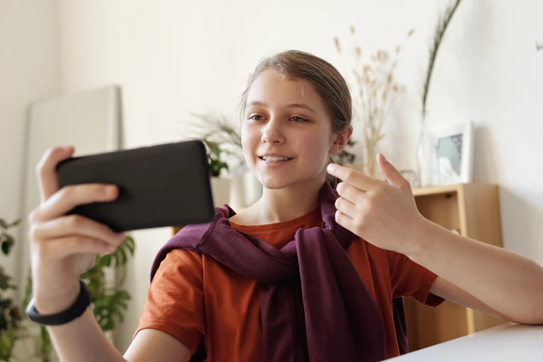 A girl takes a selfie pointing at her smile.